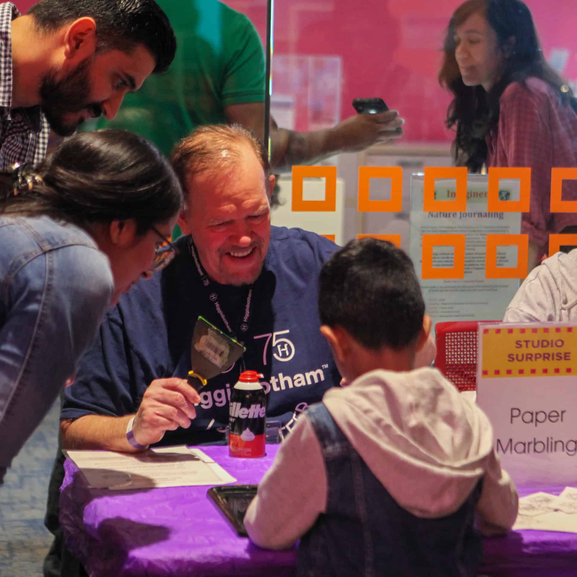 Higgenbotham volunteer smiles while helping young musuem guest complete an activity.